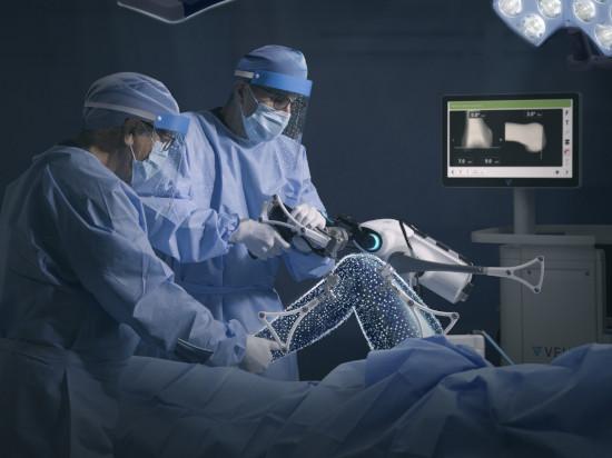 Orthopaedic surgeons performing knee replacement surgery with assistance of robot